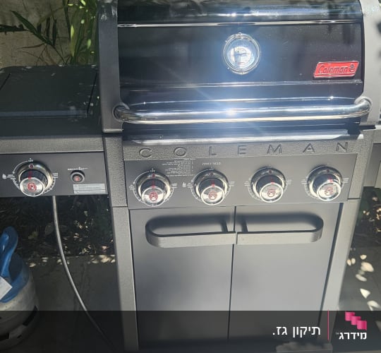 גריל גז של חברת קולמן בחצר עם בלון גז